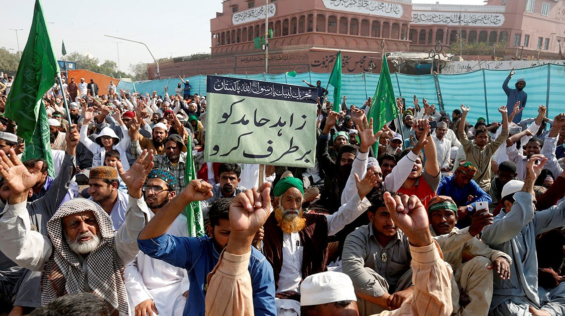 A supporter of the Tehreek-e-Labaik Pakistan, an Islamist political party, holds a sign, which reads in Urdu, "remove Zahid Hamid" during a sit-in protest along a main road in Karachi